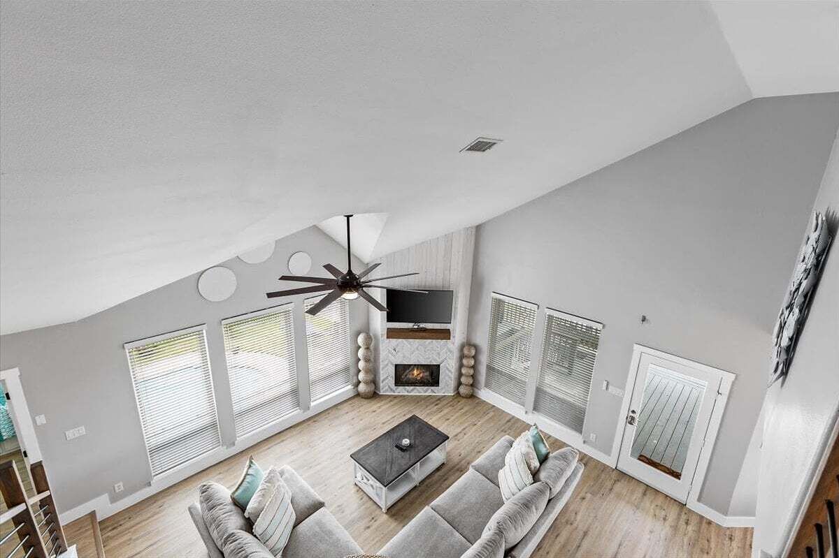 Una sala de estar moderna con ventilador de techo, chimenea y televisor.