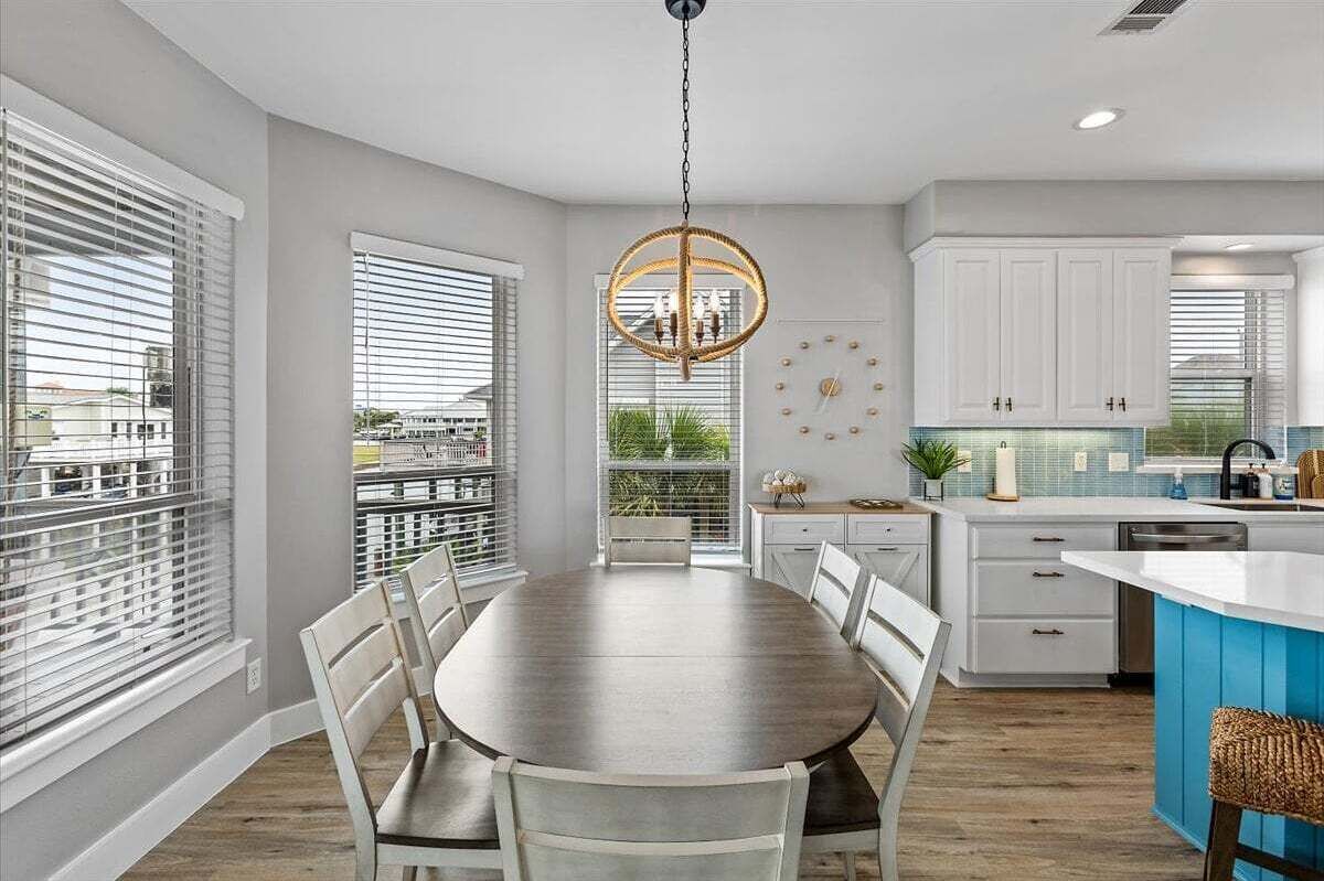 A modern kitchen with white cabinetry, a round dining table, and a blue accent wall.