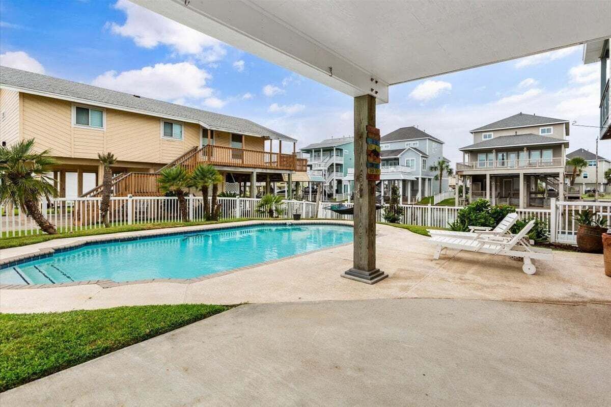 Um bairro residencial com piscina, cercas brancas e casas com varandas.