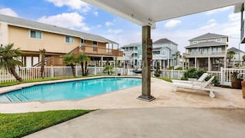 Um bairro residencial com piscina, cercas brancas e casas com varandas.