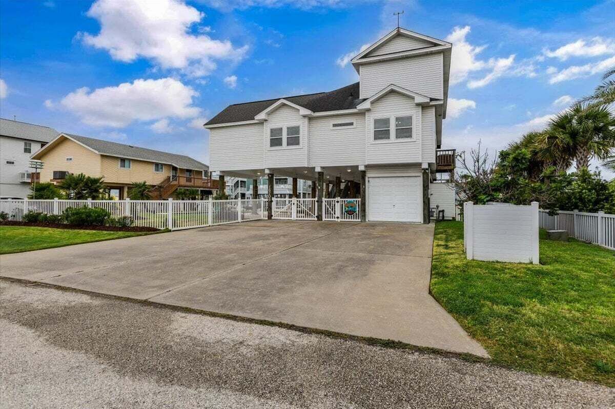 Uma casa de dois andares com garagem, varanda coberta e entrada com portão.