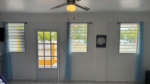 A room with a ceiling fan, a door with a view, and windows with curtains. - 5 suites privadas frente a la playa en Bo Bajos Villa Pesquera Patillas: (Lamboglia)