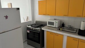 A kitchen with a gas stove, oven, microwave, and yellow cabinets. - 5 suites privadas frente a la playa en Bo Bajos Villa Pesquera Patillas: (Lamboglia)