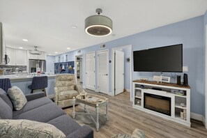 Ein Wohnzimmer mit einer Couch, einem Couchtisch, einem Fernseher und einem Kamin.