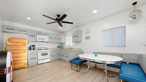 A compact kitchen with a dining area, a ceiling fan, and a window with blinds. - North Park 3BR Furnished Rental—31-Night Minimum (San Diego)