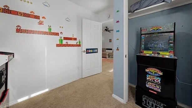 A hallway with a white door, a ceiling fan, and a wall with game-themed decorations. - North Park 3BR Furnished Rental—31-Night Minimum (San Diego)
