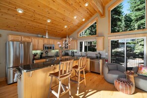 Une cuisine dotée de meubles en bois, d’appareils électroménagers en acier inoxydable et d’un grand îlot central avec des tabourets de bar.