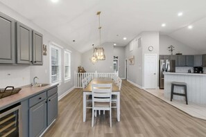 A spacious kitchen with a dining area, white cabinetry, and a modern chandelier. - 5754 - An Unforgettable Vacation - Luxury Oceanfront | Private Pool & Game Room (Nags Head)