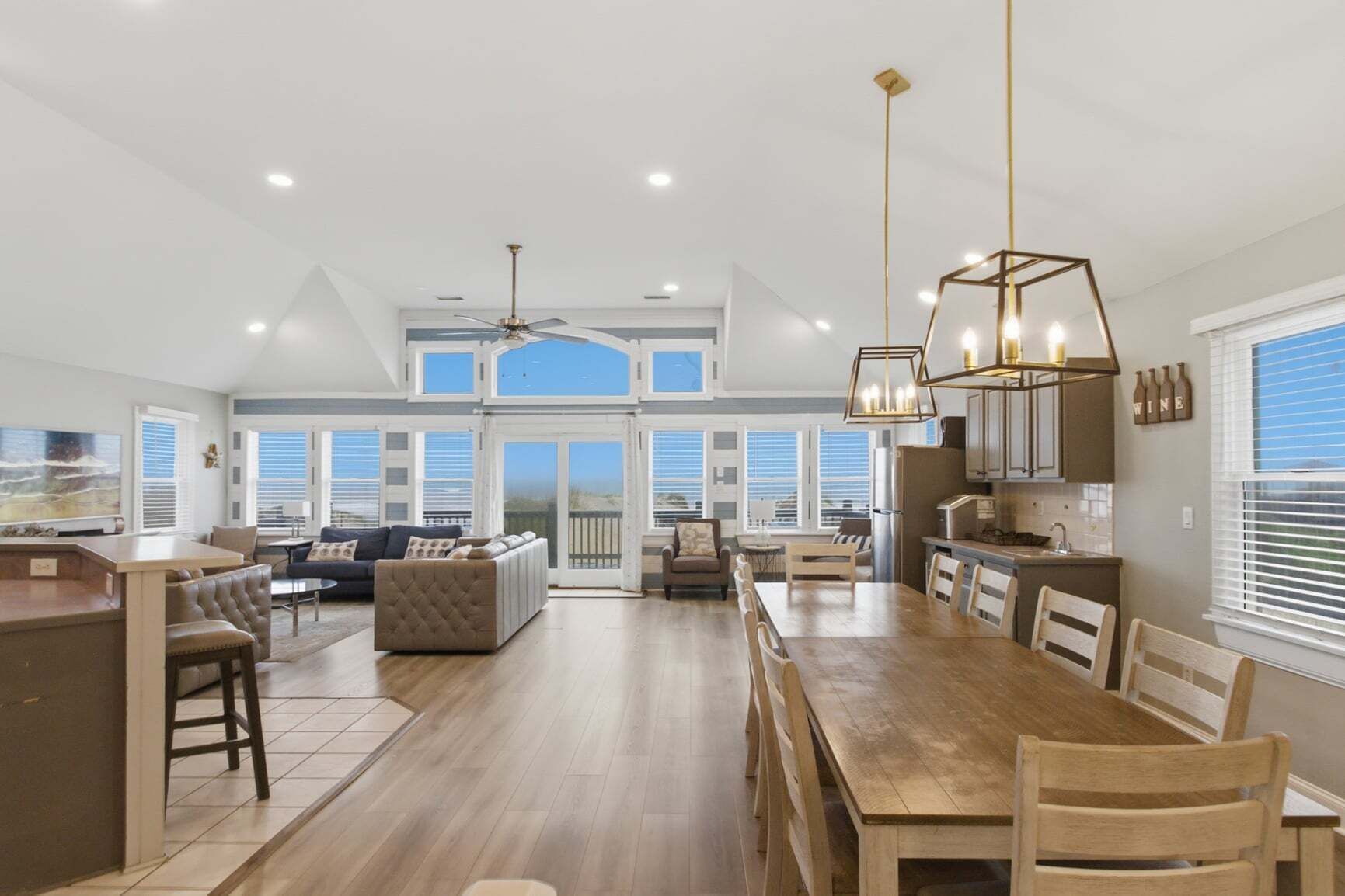 A spacious kitchen with a dining area, large windows, and a ceiling fan.