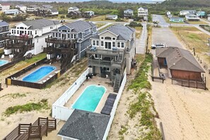 A residential area with multiple houses, a swimming pool, and a beach. - 5754 - An Unforgettable Vacation - Luxury Oceanfront | Private Pool & Game Room (Nags Head)
