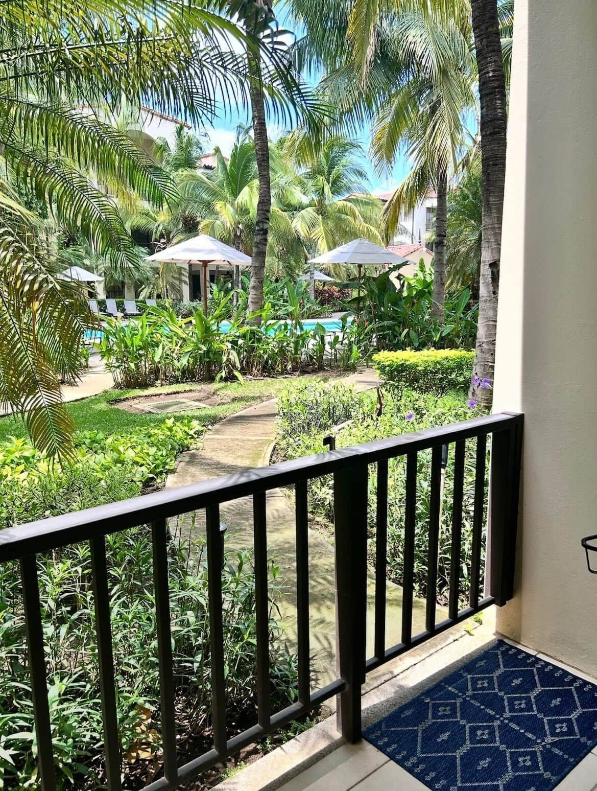 Un balcon avec vue sur une piscine et des palmiers.
