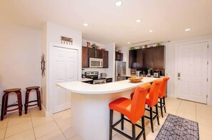 A modern kitchen with a central island, bar stools, and built-in appliances. - Ground Floor 2BR with walk-out pool access (playas del coco)