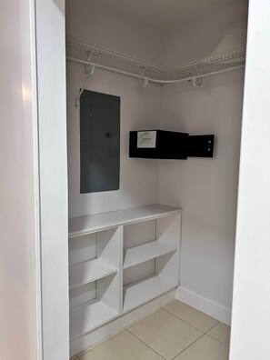 A small, enclosed storage space with a white door, a metal electrical panel, and a black shelf unit. - Ground Floor 2BR with walk-out pool access (playas del coco)