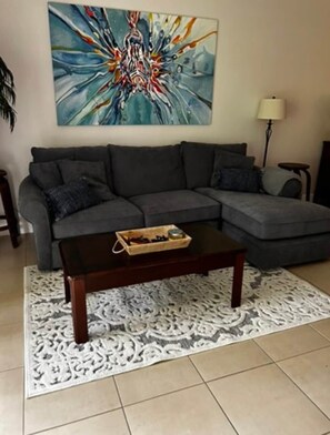 Ein Wohnzimmer mit Ecksofa, Couchtisch und einem dekorativen Teppich.