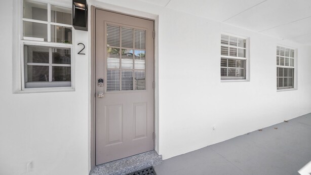 A building facade with a numbered door, three windows, and a metal stairway. - 600 #2 Managed by Brampton Park (Deerfield Beach)