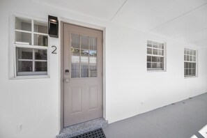 A building facade with a numbered door, three windows, and a metal stairway. - 600 #2 Managed by Brampton Park (Deerfield Beach)