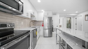 A modern kitchen with stainless steel appliances, white cabinetry, and a marble countertop. - 600 #2 Managed by Brampton Park (Deerfield Beach)