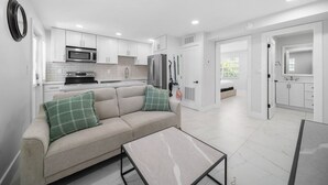 A modern kitchen with white cabinets, a microwave, stove, and refrigerator. - 600 #2 Managed by Brampton Park (Deerfield Beach)