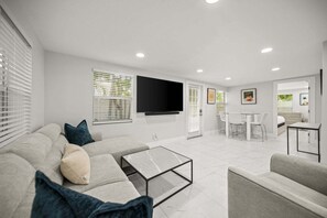 Ein modernes Wohnzimmer mit Sofa, Couchtisch und Fernseher.