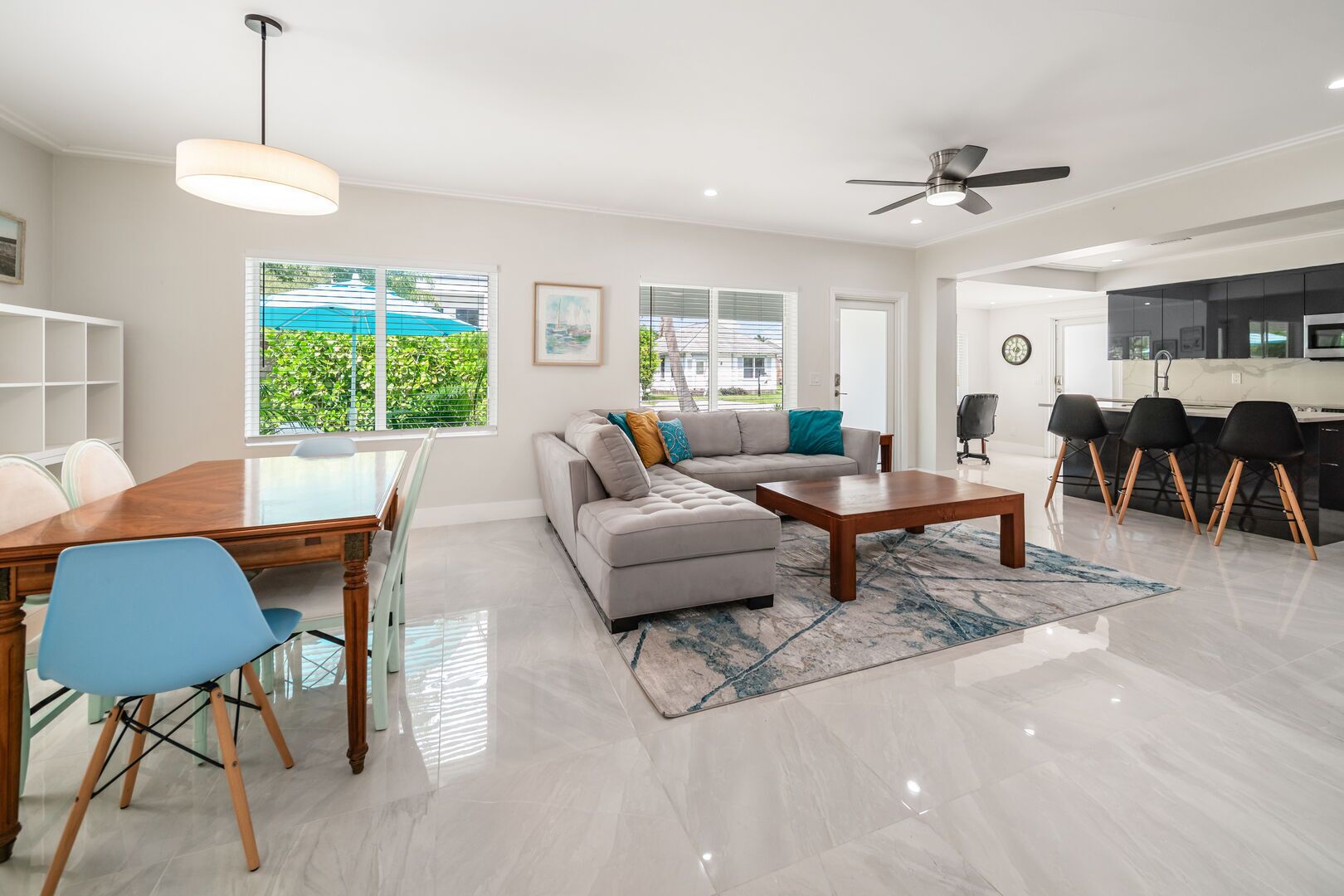 A modern living room with a dining table, sofa, and kitchen area.