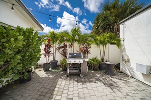 A patio area with a barbecue grill, potted plants, and a clear blue sky. - 237 Managed by Brampton Park (Delray Beach)