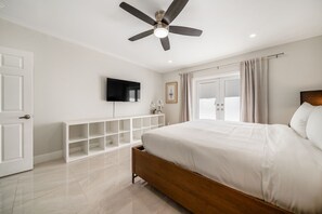 A bedroom with a bed, a ceiling fan, a TV, and a window with curtains. - 237 Managed by Brampton Park (Delray Beach)