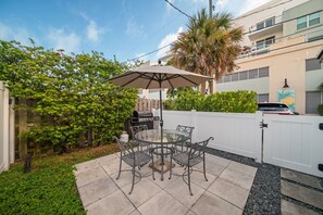 A patio with a glass table and chairs, a barbecue grill, and a white fence. - 237B Managed by Brampton Park (Delray Beach)