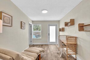 Ein Zimmer mit Holzboden, einem Esstisch mit Stühlen, einer Bank und gerahmten Kunstwerken an den Wänden.