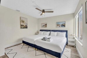 Ein Schlafzimmer mit einem Bett, einem Deckenventilator und Kunstwerken an den Wänden.