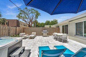 Ein Garten mit Whirlpool, Sitzgelegenheit im Freien und einem Grill.
