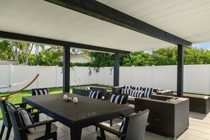 An outdoor patio with a table and chairs, a hammock, and a white fence in the background. - 15 Managed by Brampton Park (Delray Beach)