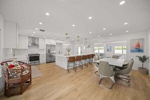 A modern kitchen with white cabinetry, a central island, and bar stools. - 15 Managed by Brampton Park (Delray Beach)