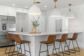 A modern kitchen with a central island, stainless steel appliances, and pendant lighting. - 15 Managed by Brampton Park (Delray Beach)