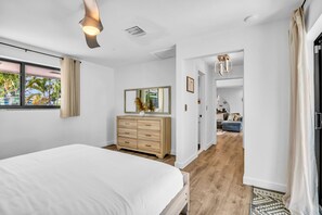A bedroom with a bed, a dresser, a mirror, and a view of a pool. - 1750 Managed by Brampton Park (Pompano Beach)