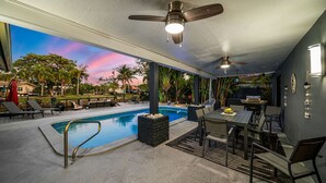 A poolside area with a pool, lounge chairs, a dining table, and ceiling fans. - 1750 Managed by Brampton Park (Pompano Beach)