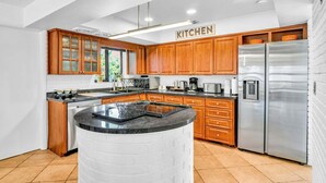 A modern kitchen with wooden cabinets, a stainless steel refrigerator, and a central island. - 1750 Managed by Brampton Park (Pompano Beach)