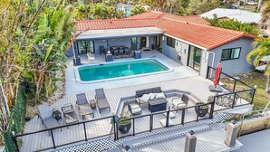 Una casa moderna amb piscina, mobiliari exterior i teulada de rajoles vermelles.