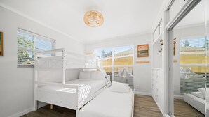 Habitació amb un llit superposat, un llit individual, una finestra gran i vista a l'exterior.