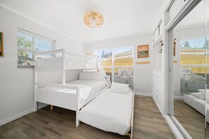Quarto com beliche, uma cama de solteiro, uma janela grande e vista para o exterior.