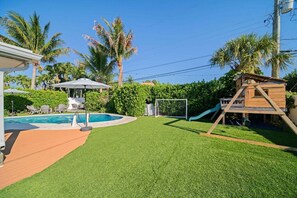 Ein Garten mit Swimmingpool, Spielhaus aus Holz und Fußballtor.