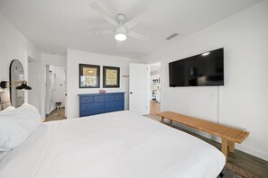 A bedroom with a large bed, a wooden bench, a ceiling fan, a flat-screen TV, and a dresser. - 1005 Managed by Brampton Park (Deerfield Beach)