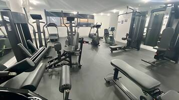 Un gimnasio con diverso equipamiento de ejercicio, incluyendo cintas de correr, máquinas de pesas y bancos.