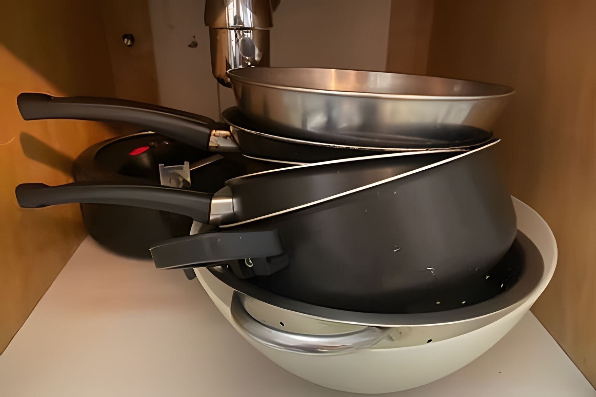Et køkken med komfur, gryder og pander stablet på en hvid bordplade.