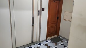 A hallway with a white door, a wooden door, and a tiled floor. - SHB Lazer completo no melhor do Guarujá (Guarujá)