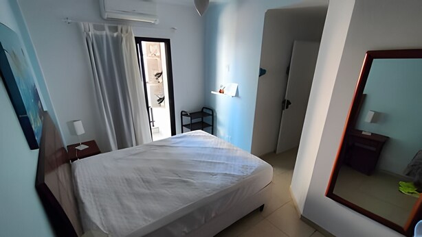 A bedroom with a bed, a mirror, a door, and a small table. - SHB Lazer completo no melhor do Guarujá (Guarujá)