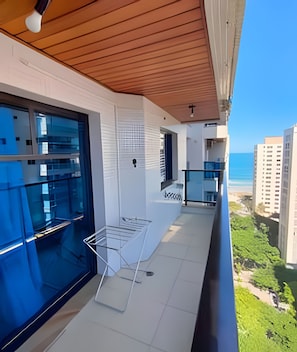 A balcony with a view of the ocean, a hanging light fixture, and a metal drying rack.