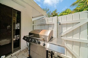 An outdoor grill with a chimney, a gas supply line, and a white fence in the background. - 2219 Managed by Brampton Park (Delray Beach)