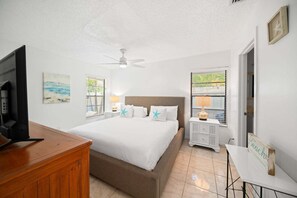 Ein Hotelzimmer mit Bett, Fernseher, Schreibtisch und einem Fenster mit Jalousien.