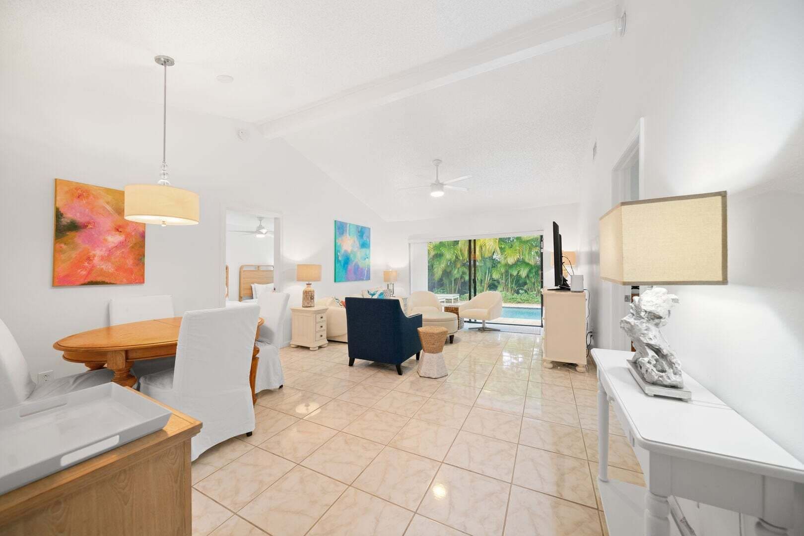 A spacious living area with a dining table, comfortable seating, a television, and artwork on the walls.