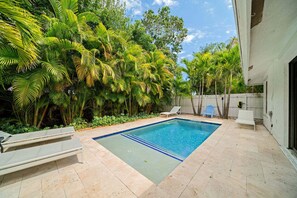 Ein rechteckiger Pool mit klarer, blauer Wasserlinie, umgeben von einer gefliesten Terrasse.